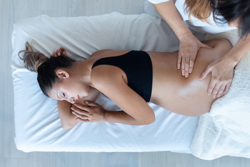 Shot,Of,Beautiful,Young,Physiotherapist,Woman,Massaging,Tummy,On,Pregnant