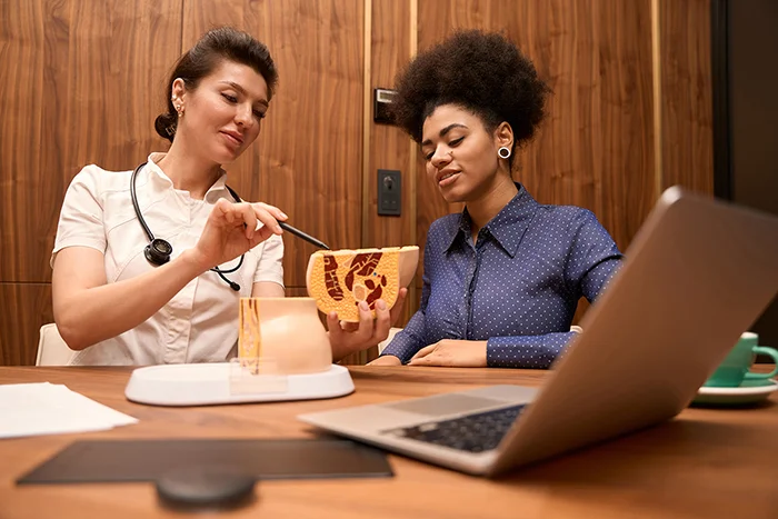 Pelvic health physiotherapist explaining pelvic floor anatomy to a woman during a consultation in a London clinic
