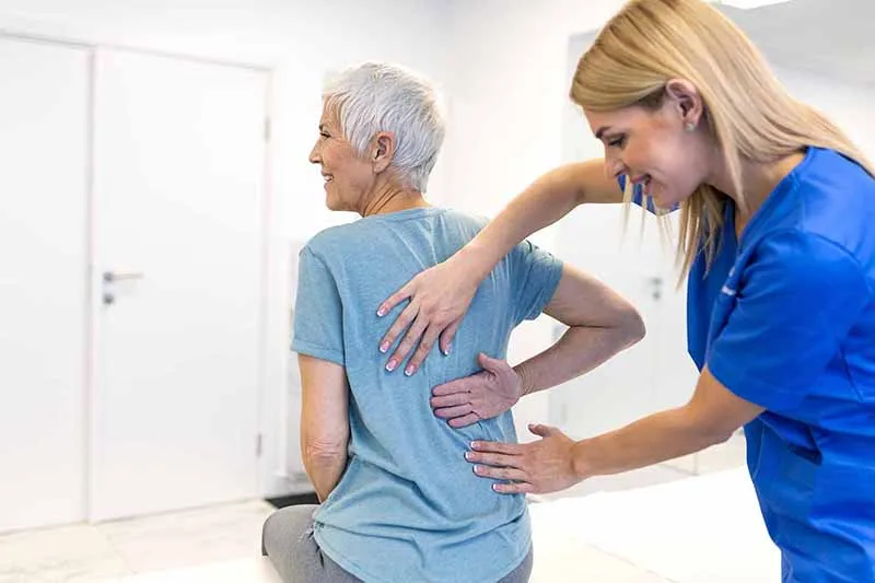 Physiotherapist assessing lower back and buttock pain in an older woman at a London physiotherapy clinic